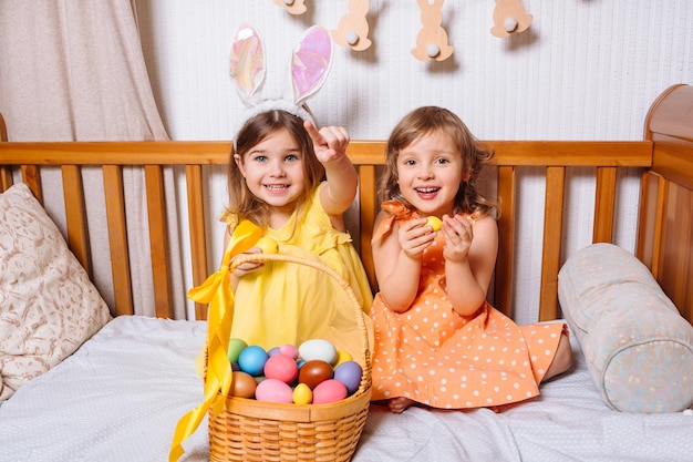 Photo deux amies drôles avec un panier rempli d'oeufs colorés pour les vacances de pâques