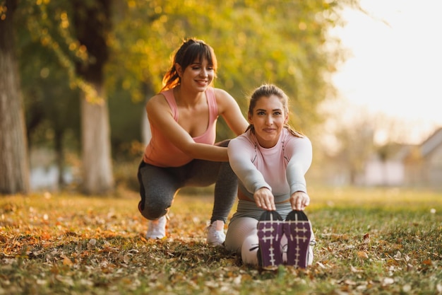 Deux amies heureuses font des exercices d'étirement dans la nature par une journée ensoleillée.