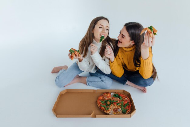 Deux amies mangeant de la pizza.