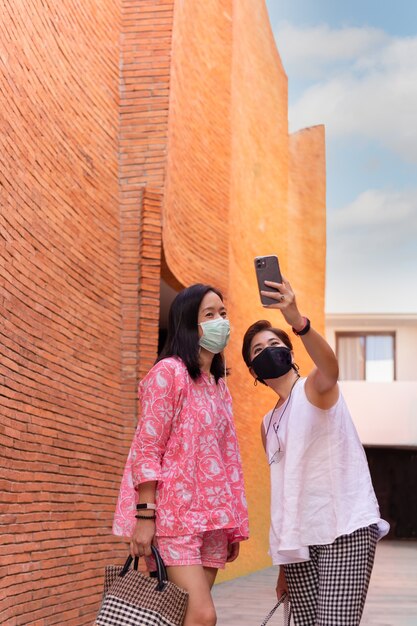 deux amies avec des masques de protection prenant un selfie à l'aide d'un téléphone portable