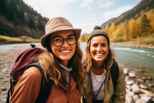 Deux amies prennent un selfie au bord de la rivière lors d'une randonnée en montagne
