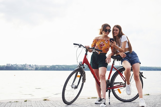 Deux amies à vélo s'amusent à la plage près du lac.