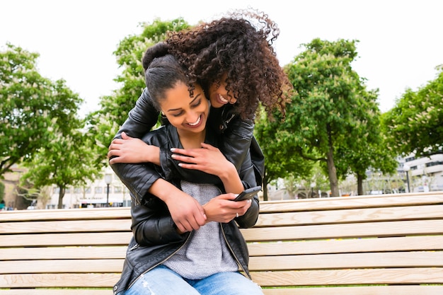 Photo deux amis adolescents d'afrique du nord lire et écrire un message texte sur téléphone mobile dans le parc