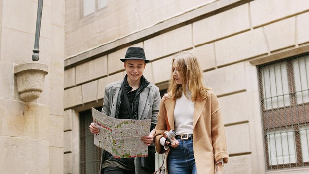 Deux amis élégants debout dans la rue et cherchent quelque chose à l'aide d'une carte. Ils regardent autour. Ils parlent et aiment marcher ensemble.