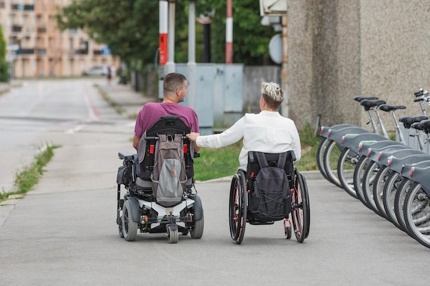 Photo deux amis en fauteuil roulant handicapés se rencontrent dans la rue de la ville pour s'amuser et