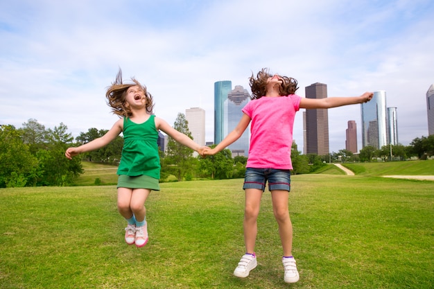 Deux amis filles sautant heureux, tenant la main dans les toits de la ville