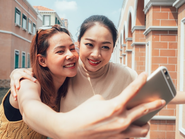 Deux amis de filles touristiques prennent selfie avec la vue sur la ville.