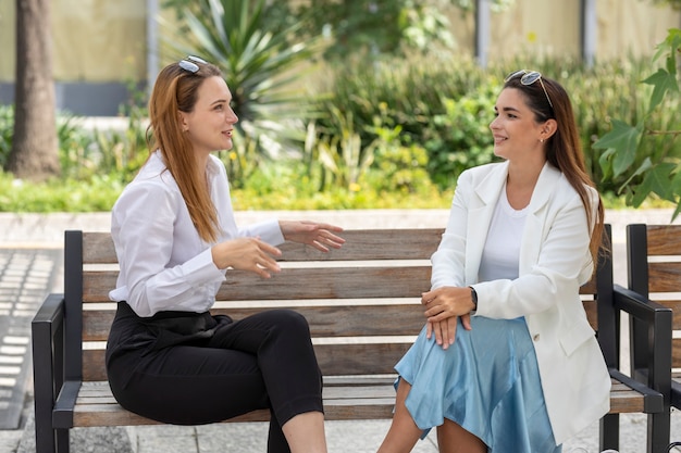 deux amis heureux parlant assis sur un banc dans la voie publique