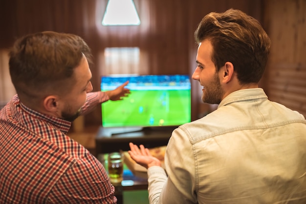 Les deux amis heureux regardent un football