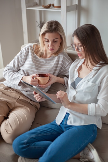 Deux amis de jeunes femmes utilisant une tablette ensemble, assis sur le co