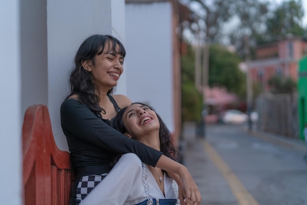 Deux amis latina rient en s'embrassant dans la rue