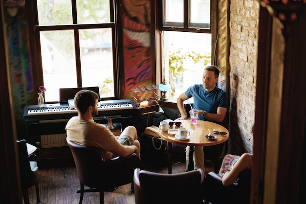 Deux amis masculins adultes assis et parlant au café