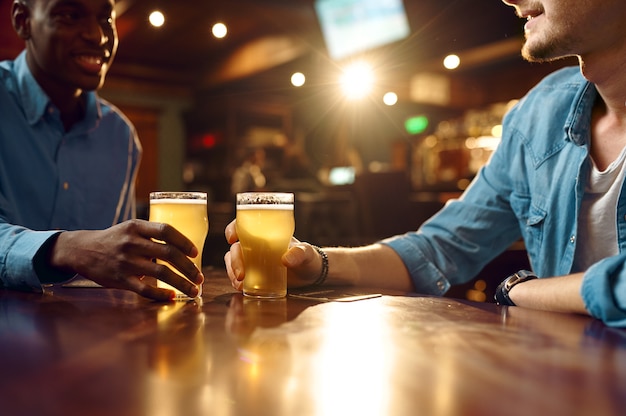 Deux amis masculins boivent de la bière fraîche au bar. Les gens se détendent dans un pub, mode de vie nocturne, amitié, célébration d'événements, loisirs pour hommes au restaurant