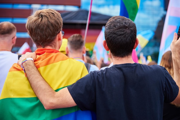 Deux amis masculins avec des drapeaux arc-en-ciel sur la démonstration de fierté