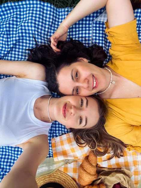 Deux amis prennent un selfie sur une couverture bleue pour un pique-nique en plein air