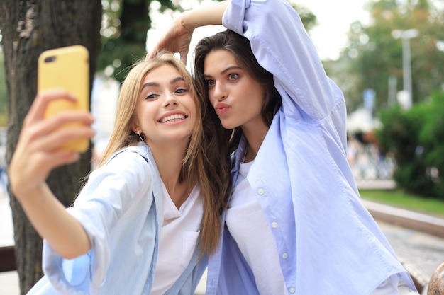 Deux amis riants profitant d'un week-end ensemble et faisant du selfie sur fond de ville.