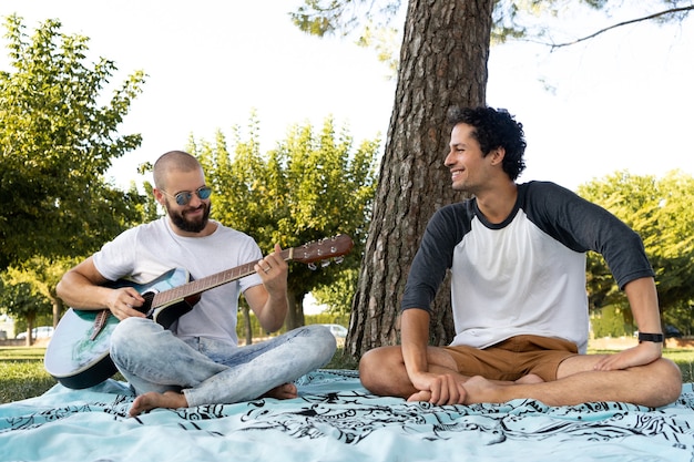 Deux amis s'amusant et jouant de la guitare dans le parc