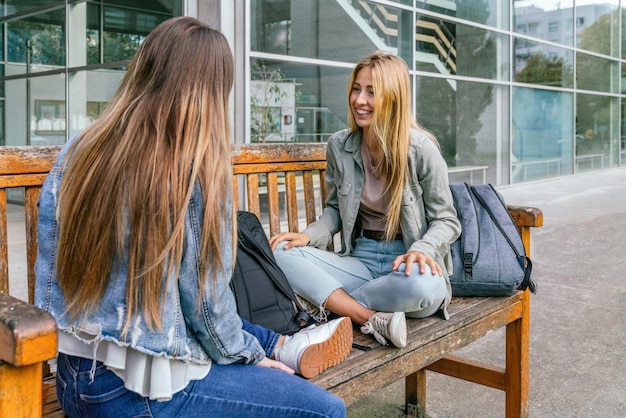 Deux amis d'université assis sur un banc se reposant et discutant par une journée ensoleillée.