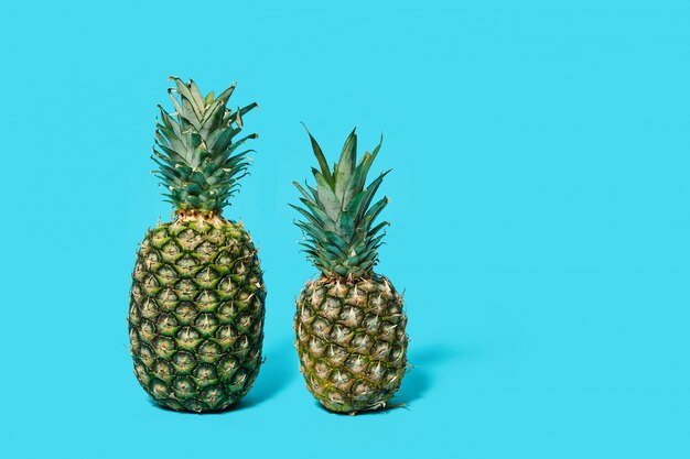 Deux ananas isolés sur une table bleue.