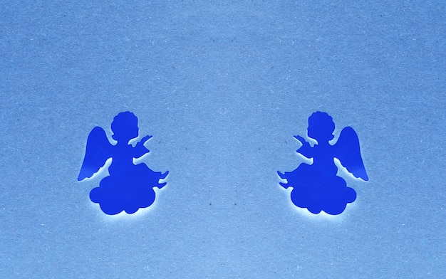 Deux anges de papier bleu foncé se regardant sur un fond de papier bleu clair