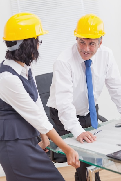 Deux architectes parlant avec un casque jaune et sourire