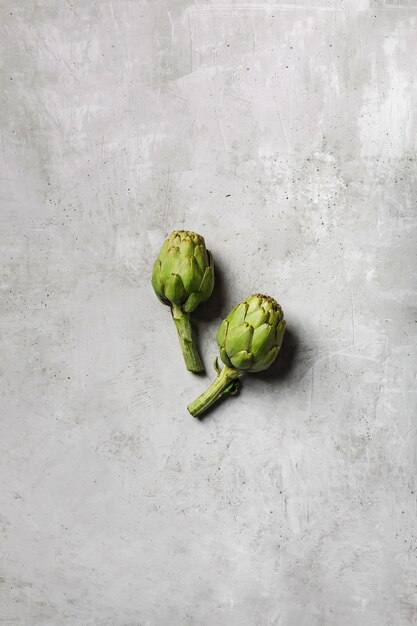 Deux artichauts frais sur une table gris clair. Légume exotique pour une alimentation et une alimentation saines.