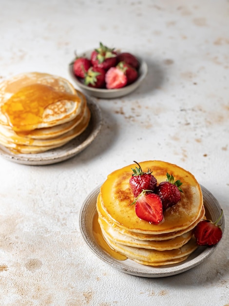 Deux assiettes de crêpes maison à la fraise et au miel sur fond texturé de style rustique