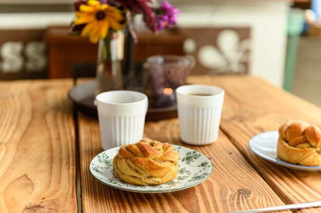 Photo deux assiettes avec un délicieux pain de cardamome sur chacune et deux cafés chauds sur une table dans un café