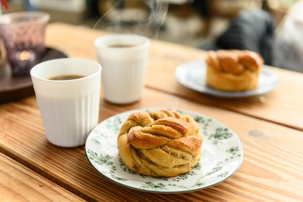 Photo deux assiettes avec un délicieux pain de cardamome sur chacune et deux cafés chauds sur une table dans un café