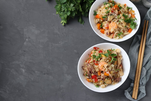 Deux assiettes de riz frit aux fruits de mer légumes gingembre et persil sur fond sombre Cuisine asiatique