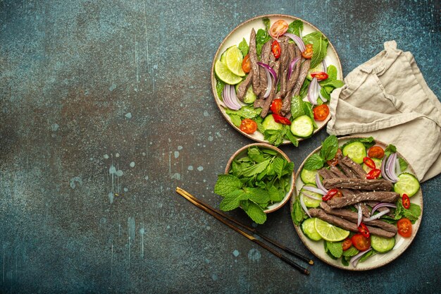 Photo deux assiettes avec une salade traditionnelle de bœuf thaïlandais avec des légumes