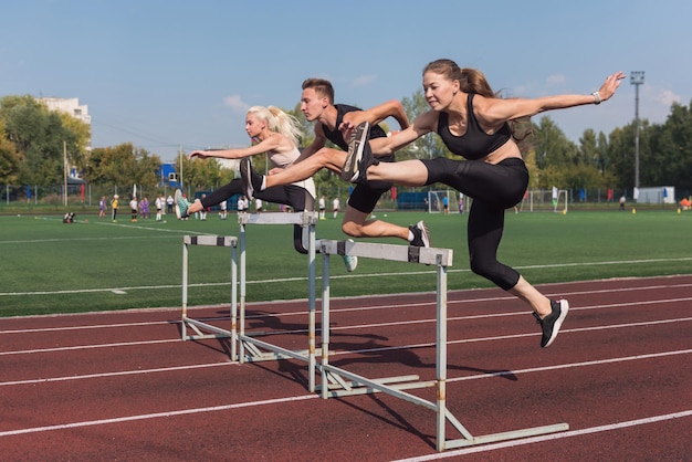 Deux athlètes femme et homme runner courir des haies au stade à l'extérieur