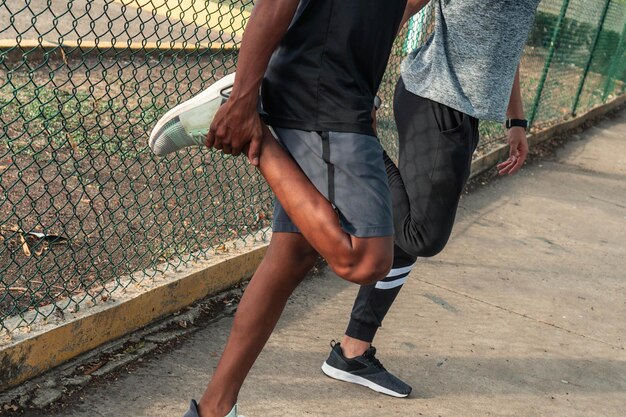 Deux athlètes masculins méconnaissables faisant des exercices d'étirement dans le parc