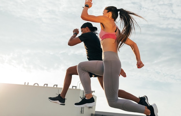 Deux athlètes sautant en l'air pendant la course Un homme et une femme sprintant ensemble sur le toit