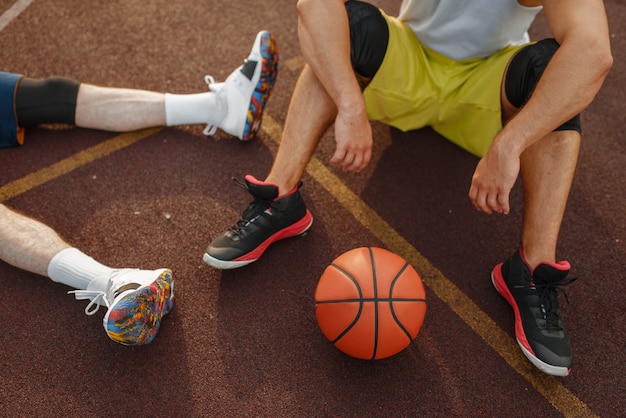 Deux basketteurs assis sur le sol sur un terrain extérieur.
