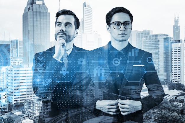 Deux beaux hommes d'affaires en costume réfléchissant aux opportunités de carrière au département de recherche et développement de la société de conseil internationale Icônes d'hologramme sur fond de Kuala Lumpur
