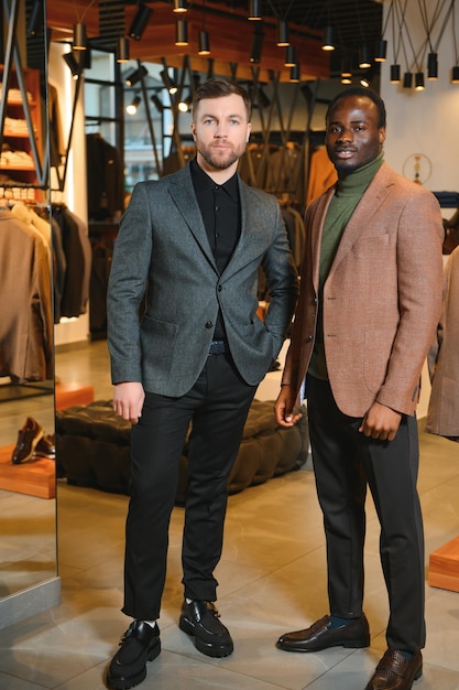 Photo deux beaux hommes respectables dans des costumes classiques élégants dans un magasin de vêtements pour hommes haut de gamme