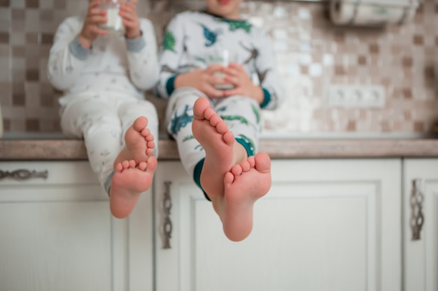 deux bébés garçons s'amusent en train de prendre leur petit déjeuner dans la cuisine en pyjama