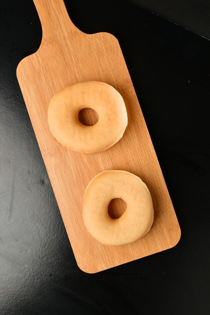 Photo deux beignets sur une planche à découper en bois sur un tableau noir.