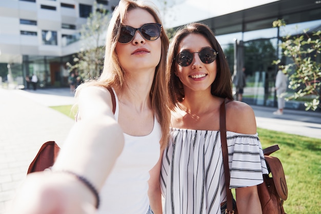 Deux belle jeune fille étudiante heureuse avec sac à dos près du campus de l'université. Concept d'éducation et de loisirs