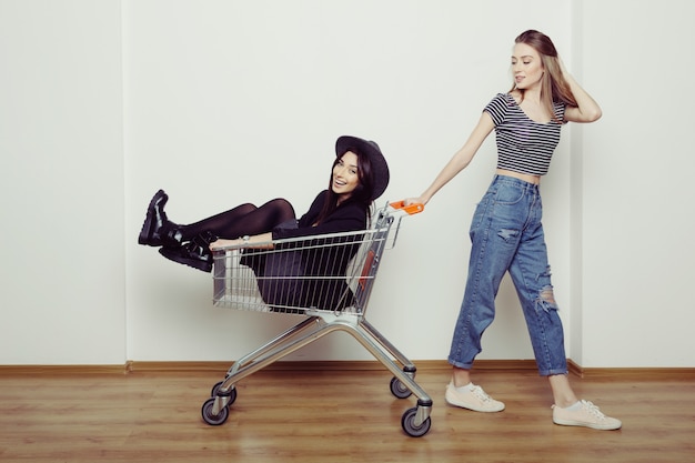 Deux belles adolescentes heureuse conduisant le panier à l'intérieur