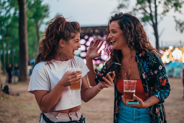 Deux belles amies utilisant un smartphone lors d'un festival de musique