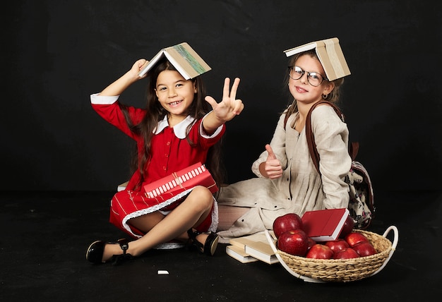 deux belles copines écolières ont un plaisir assis avec des livres