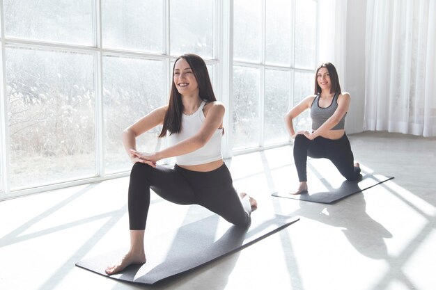 Deux belles femmes effectuant du yoga synchronisé dans un studio moderne