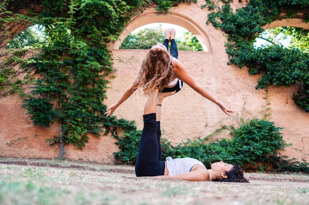 Deux belles femmes faisant de l'acroyoga dans le jardin ou le parc Harmonie et détente