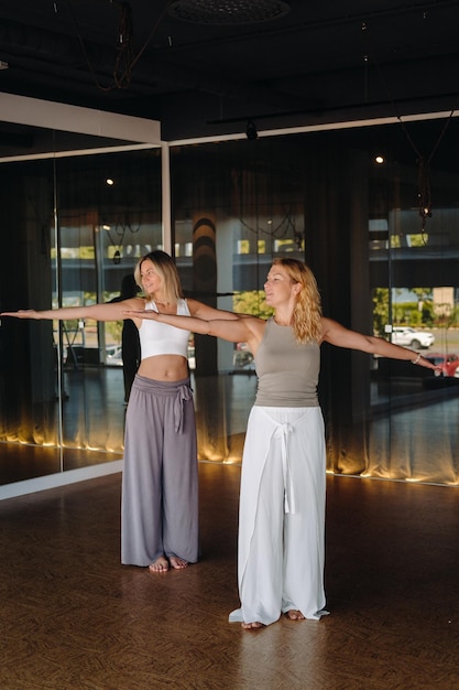 Deux belles femmes font du yoga debout dans la salle de fitness