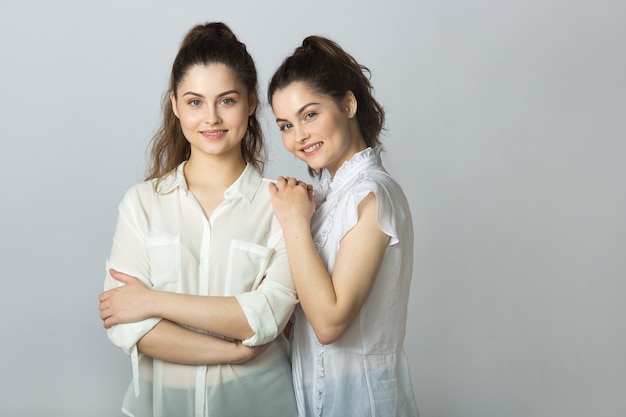 Deux belles femmes joyeuses jumelles sur fond gris