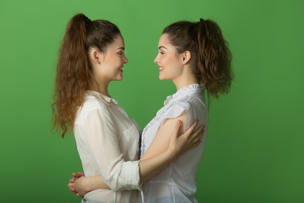 Deux belles femmes joyeuses jumelles sur fond vert