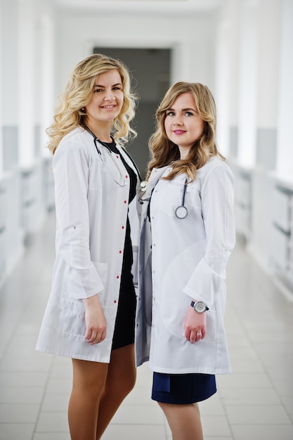Deux belles femmes médecins ou travailleurs médicaux en blouse blanche posant à l'hôpital.