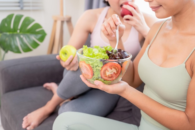 Deux belles femmes prenant un petit-déjeuner sain à la maison après une séance de yoga avec bonheur